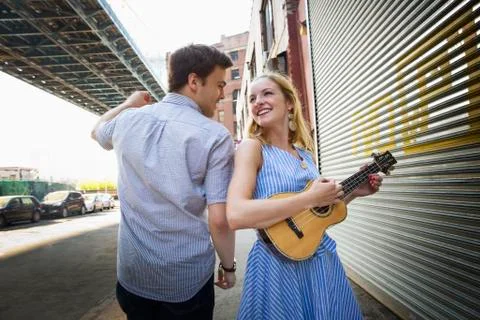 Caucasian couple playing ukulele in city Stock Photos