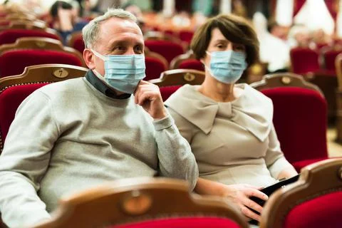 Caucasian couple senor and senora in antivirus mask in theater hall Stock Photos