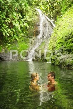 Caucasian Couple Swimming In Remote Jungle Pool
