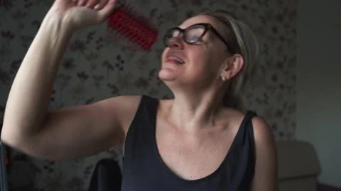 Caucasian crazy middle aged woman at home singing on hair brush. Happy positive Stock Footage