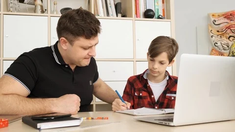 Caucasian dad explans the exaples for the hometask to his attentive son sitting Stock Footage 111334068