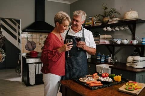 Caucasian elderly couple embracing while cooking in kitchen Stock Photos