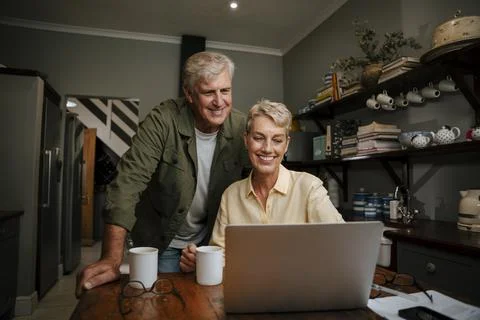 Caucasian elderly couple smiling while talking to friends on video call Stock Photos