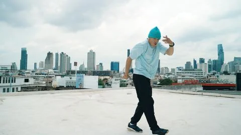 Caucasian energetic B-boy dancer practicing street dancing at rooftop. Hiphop. Stock Photos