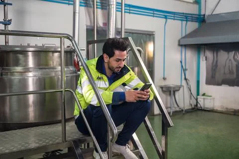 Caucasian engineer man using smartphone during break time on stair at process Stock Photos