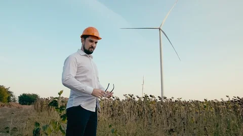 Caucasian engineer in orange protective helmet puts on goggles and looks at the Video stock 99581202