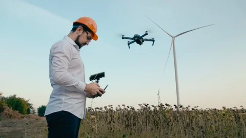Caucasian engineer in an orange protective helmet and goggles with a remote Stock Footage 99581786