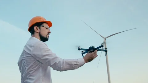 Caucasian Engineer in an orange protective helmet and goggles with a remote Stock Footage 99582129