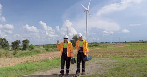 Caucasian engineer in safety uniform holding toolbox looking at wind turbines, Stock Footage 335215112