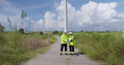 Caucasian engineer team examining wind turbine structure on rural road Stock Footage 335219596