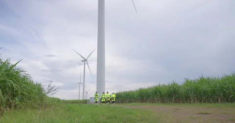 Caucasian engineer team walking along wind farm path toward turbine for Stock Footage 337165820