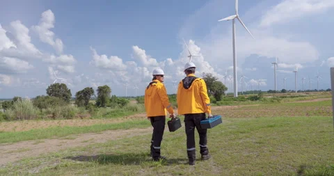 Caucasian engineer team walking toward wind turbines carrying toolbox, safety Stock Footage 321046525