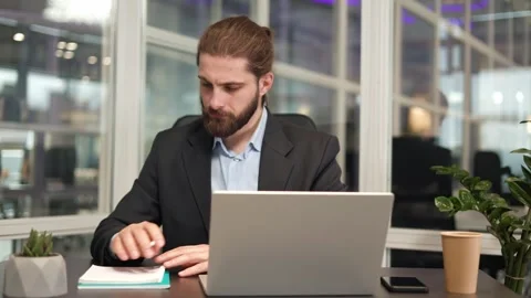 Caucasian entrepreneur making notes and working on computer in modern office Stock Footage 256961010
