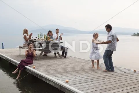 Caucasian Family Cheering As Father And Daughter Dance On Pier Over Lake