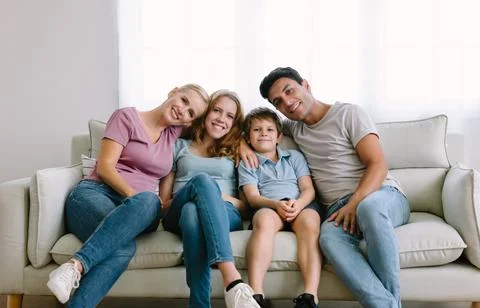 Caucasian family with liite boy and teenage girl sitting on sofa smile at camera Stock Photos