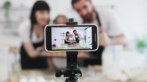 Caucasian family recording baking tutorial with smartphone in a modern kitchen 스톡 동영상 306478090