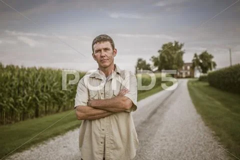 Caucasian farmer standing on dirt road by corn field Stock Photos