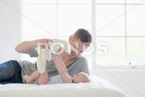 Caucasian Father And Baby Playing With Stuffed Animal In Bedroom
