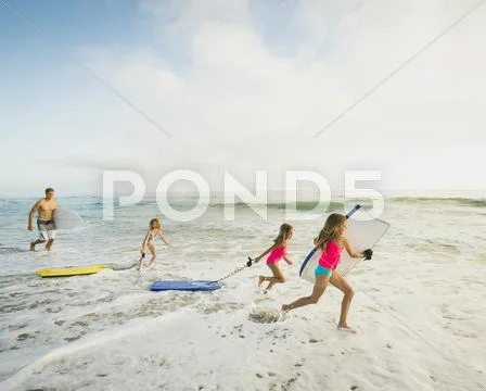 Caucasian Father And Daughters Playing In Waves On Beach