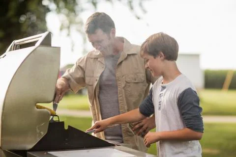 Caucasian father and son grilling food in backyard Stock Photos