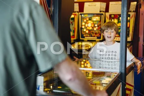 Caucasian father and son playing game in arcade Stock Photos