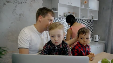 Caucasian father with two sons watching cartoons on the laptop in the kitchen Video stock 91754853