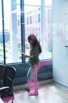Caucasian female creative worker using tablet computer standing next to window Stock Photos
