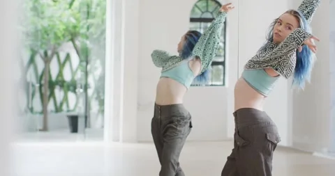 Caucasian female dancer dancing alone in front of mirror in dance studio, slow Stock Footage 342715591