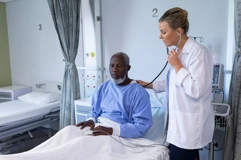 Caucasian female doctor examining with stethoscope african american male patient Stock Photos