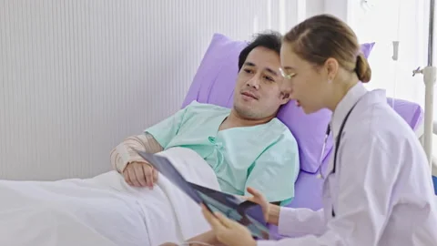 Caucasian female doctor explaining brain X-ray film to Asian male patient Stock Footage 218462653