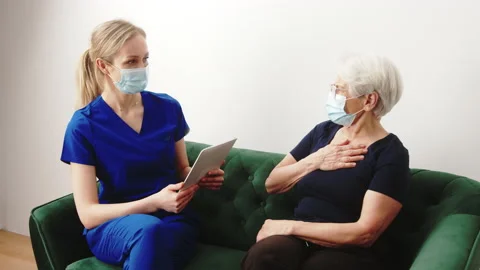 Caucasian female doctor has a home visit with her elderly grey-haired patient. Stock Footage