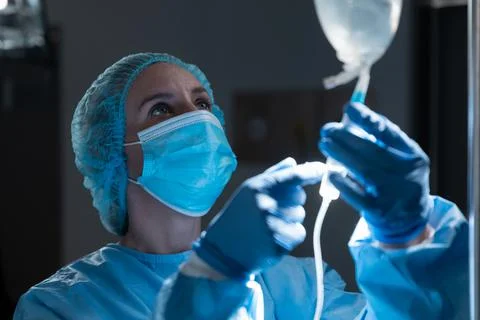 Caucasian female doctor wearing face mask preparing iv drip bag for operation Stock Photos