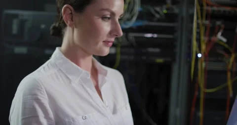 Caucasian female it technician using laptop and checking computer server Stock Footage 338167146