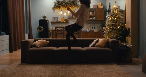 Caucasian female jumping to sofa checking her phone during Christmas holidays Stock Footage 119298443
