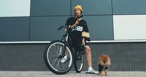 Caucasian female posing on a bicycle with her Pomeranian Spitz dog puppy outdoor Stock Footage