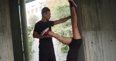 Caucasian female standing on head down leaning on hands and man holding her Video stock 123662426