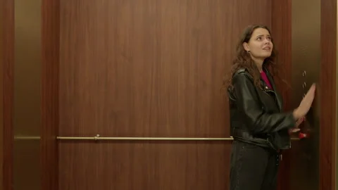 Caucasian female stuck in the elevator, pushing all buttons in anxiety Stock Footage 221623047