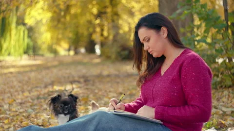 A Caucasian female student makes notes in a notebook while preparing for classes Stock Footage 262144189