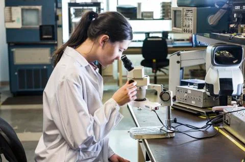A caucasian female technician using a microscope in research and development Stock Photos