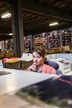 A caucasian female worker working on a computer problem in a distribution Stock Photos