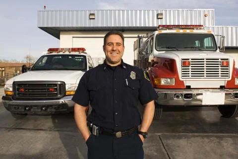 Caucasian firefighter smiling near fire trucks Stock Photos