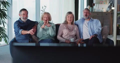 Caucasian four grey-haired old happy people gathering at home, watching TV shows Stock Footage 148285550