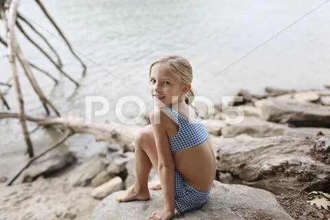 Caucasian girl in bikini sitting by remote lake Stock Photos