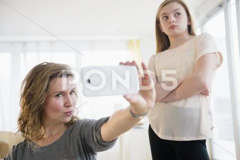 Caucasian girl embarrassed of mother taking selfies with cell phone Stock Photos