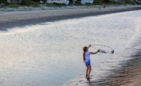 Caucasian girl fishing with net on beach Stock Photos