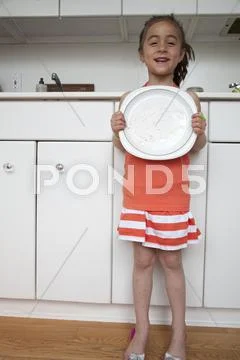 Caucasian girl holding empty plate in kitchen Stock-Fotos