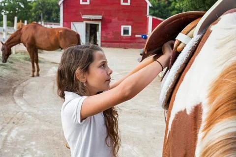 Caucasian girl saddling horse on ranch Stock Photos