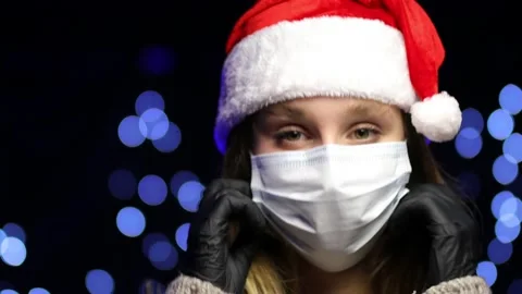 A caucasian girl in a Santa hat straightens a medical mask. Stock Footage