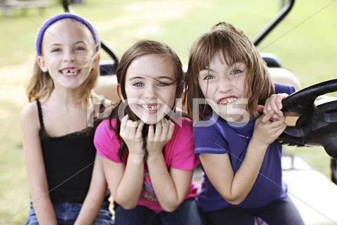 Caucasian girls making faces in golf cart Stock Photos