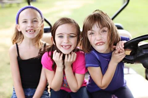 Caucasian girls making faces in golf cart Stock Photos